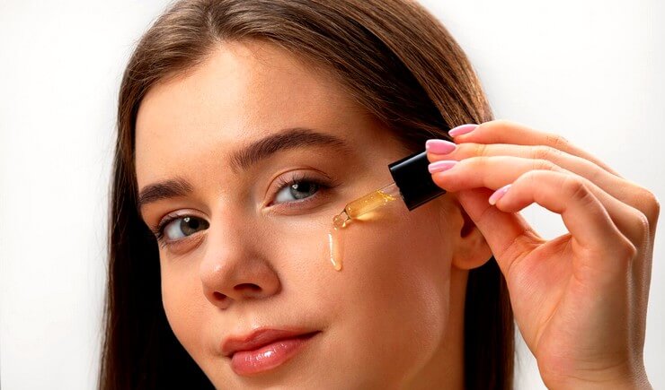 Jeune femme met de l'huile sur son visage